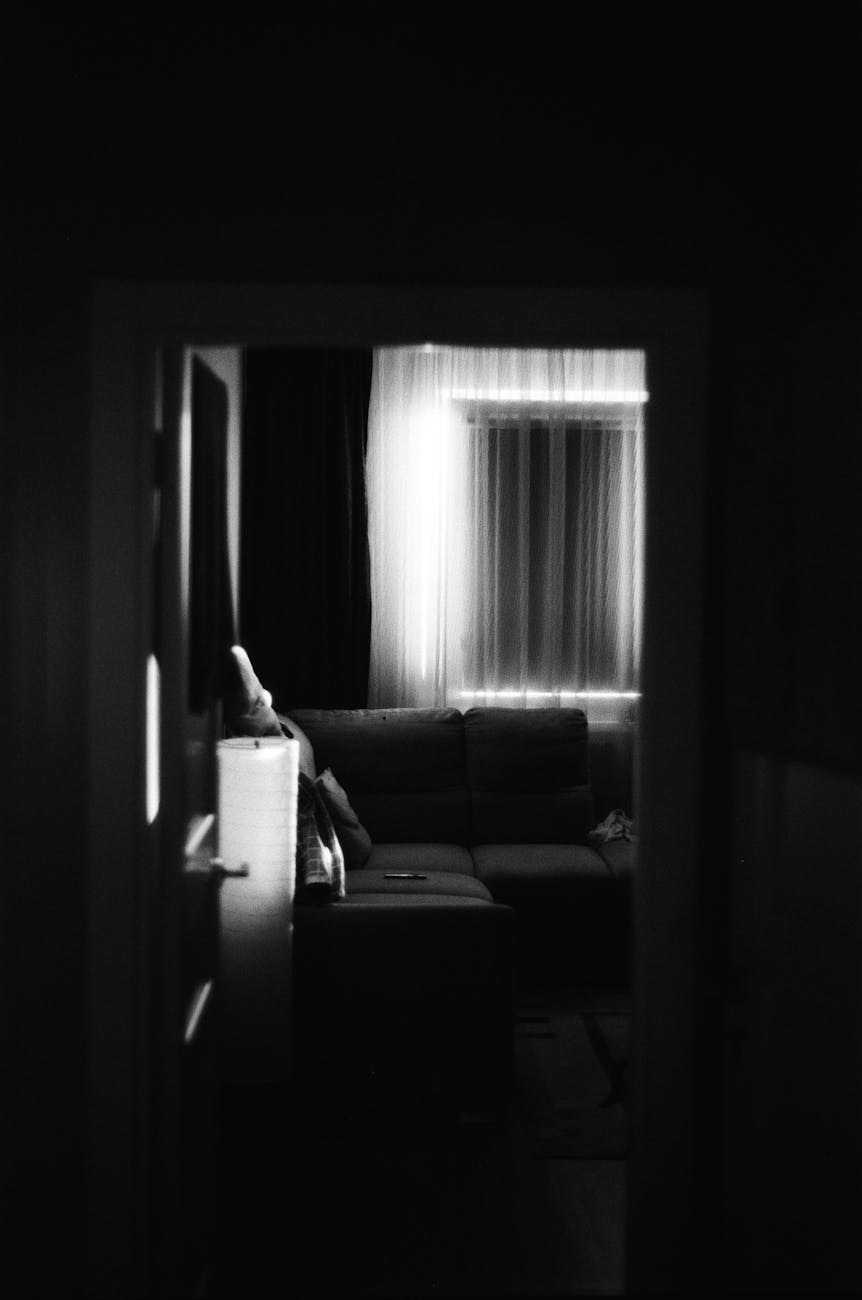 A picture in black and white of a dark room with a sofa and a candle in the frame